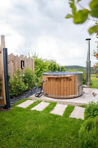un bain à remous dans un jardin avec une clôture dans l'établissement Spa nordique avec vue sur la campagne, à Saint-Paul-Lizonne