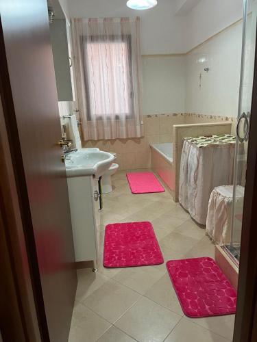 a bathroom with pink mats on the floor and a sink at Casa Salinella in Torre Nubia