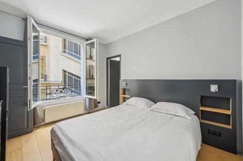 une chambre avec un grand lit blanc et une fenêtre dans l'établissement Terne Maillot - Gaston Bertandeau 1dbr, à Paris