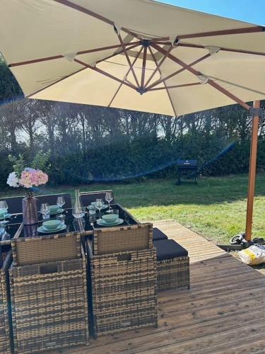 a picnic table under an umbrella on a wooden deck at Gîte au haras La Belle in Émanville