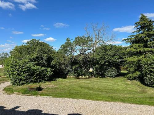 a park with trees and grass and a gravel road at Gîte au haras La Belle in Émanville