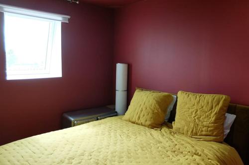 a bedroom with a bed with yellow sheets and a window at Gîte au haras La Belle in Émanville