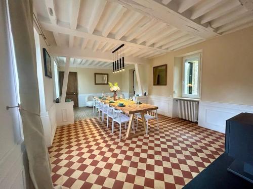 a dining room with a table and a checkered floor at Gîte au haras La Belle in Émanville