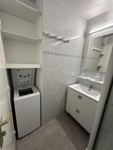 une salle de bain blanche avec un lavabo et un miroir dans l'établissement Appartement front de mer avec piscine et accès direct plage à St Cyprien, à Saint-Cyprien