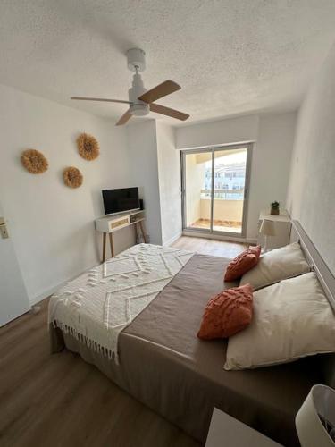 une chambre avec un grand lit avec un ventilateur de plafond dans l'établissement Appartement front de mer avec piscine et accès direct plage à St Cyprien, à Saint-Cyprien