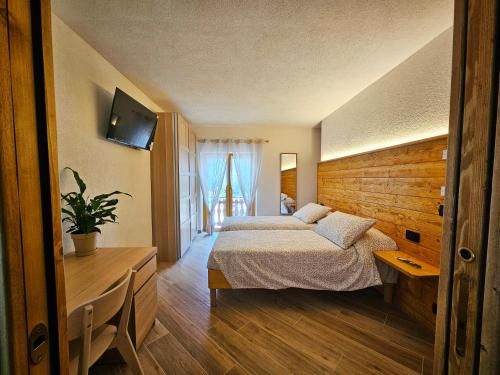 a bedroom with a bed and a desk and a television at La Genzianella affittacamere in Santo Stefano dʼAveto