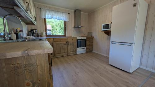 a kitchen with a white refrigerator and wooden floors at Weistad in Heidal