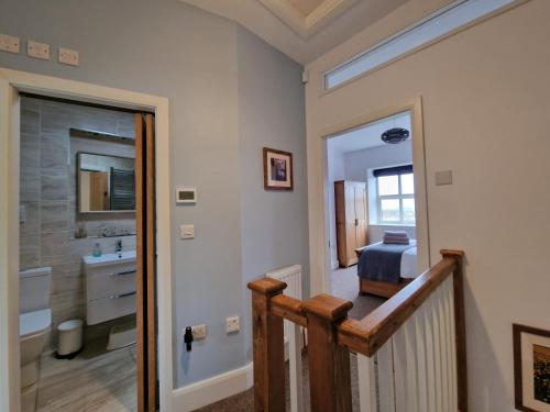 - un couloir avec une salle de bains pourvue d'un lavabo et d'une douche dans l'établissement Law Common Cottage, à Hepworth