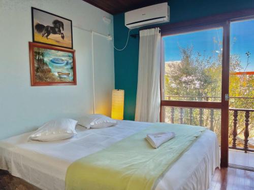 a bedroom with a large bed and a large window at Sonho da Serra Pousada in Bento Gonçalves