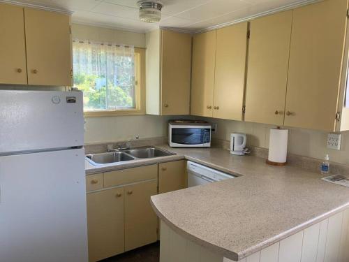 a kitchen with a white refrigerator and a sink at Historic Hillside Vacation Home in Twillingate