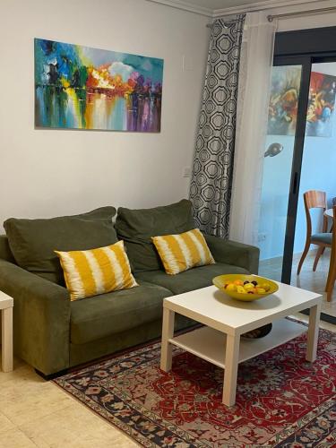 ein Wohnzimmer mit einer grünen Couch und einem Tisch in der Unterkunft Precioso apartamento con vistas al mar in Benicàssim