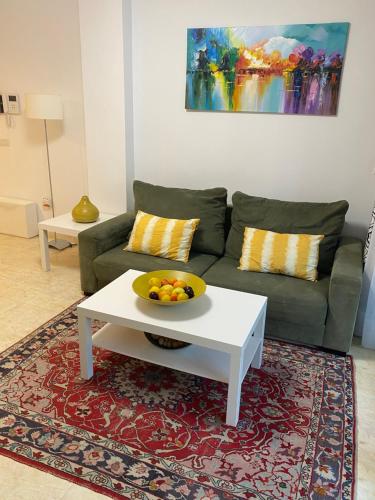ein Wohnzimmer mit einem Sofa und einer Obstschale auf einem Couchtisch in der Unterkunft Precioso apartamento con vistas al mar in Benicàssim