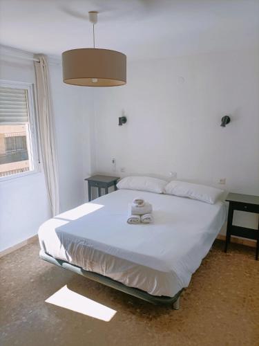 a white bed in a room with two tables at Apartamento Monet Playa in Rincón de la Victoria