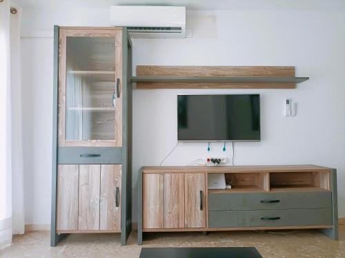 a living room with a tv and a wooden entertainment center at Apartamento Monet Playa in Rincón de la Victoria