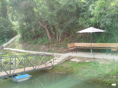 a wooden bridge with a bench and an umbrella at Splav na dan AXA in Barič