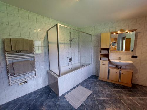 a bathroom with a shower and a tub and a sink at Landhaus Irena - Familienfreundliches Ferienhaus an der Zillerpromenade mit Bergblick in Ramsau im Zillertal