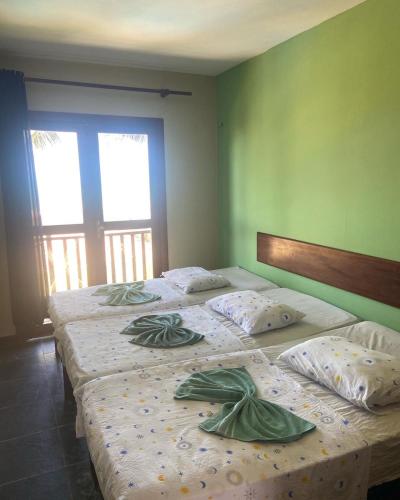 two beds in a bedroom with green walls at Residencial Sirius Canoa in Canoa Quebrada