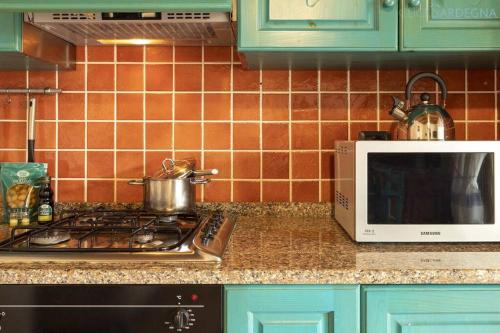 a kitchen counter with a stove and a microwave at Olivastri Cottage with pool in the Nature Park of Porto Conte in Santa Maria la Palma