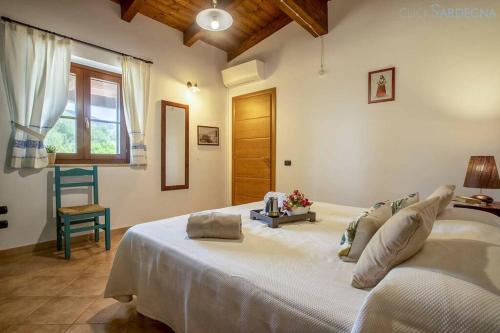 a large white bed in a room with a window at Olivastri Cottage with pool in the Nature Park of Porto Conte in Santa Maria la Palma