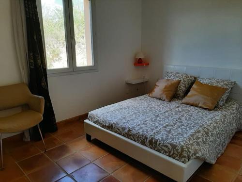 une chambre avec un lit, une chaise et une fenêtre dans l'établissement Villa les Lauriers, à Valensole