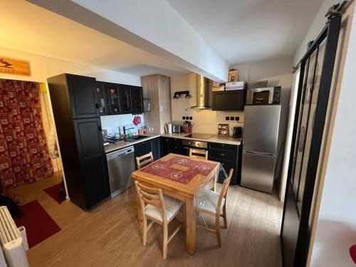 une cuisine avec une table en bois et une cuisine avec des appareils en acier inoxydable dans l'établissement Praloup 1500 Appart 4 couchages, à Uvernet