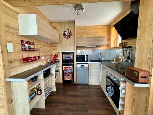 Il comprend une cuisine dotée de murs en bois et d'un réfrigérateur. dans l'établissement Appartement cosy avec jardin et barbecue, à Gérardmer
