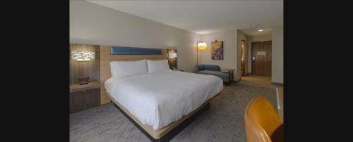 a hotel room with a large bed and a chair at Holiday Inn Express Hartford-Newington by IHG in Newington