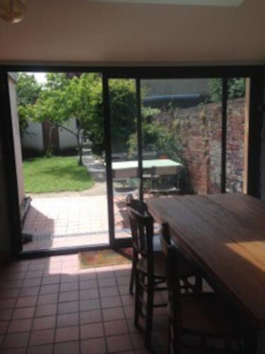 - une table à manger avec vue sur le patio dans l'établissement Loue mancelle typique Le Mans Gare, au Mans