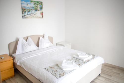 a white bed with white pillows and a picture on the wall at Olimp 35 in Olimp