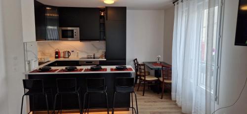 une cuisine avec un îlot noir et un comptoir dans l'établissement Le grand palais, à Drancy