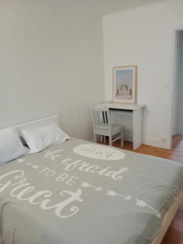 une chambre avec un lit avec un bureau et un couvre-lit sur lequel on peut lire uniquement boire dans l'établissement Appartement à 10mn de paris, à Vitry-sur-Seine