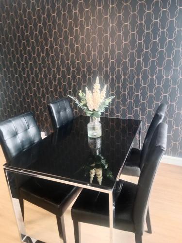 une table de salle à manger noire avec des chaises noires et un mur à motifs dans l'établissement Appartement à 10mn de paris, à Vitry-sur-Seine