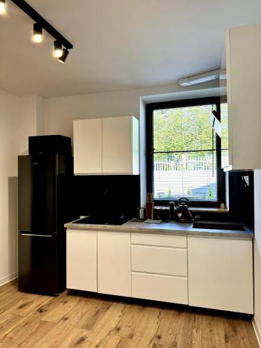 a kitchen with white cabinets and a black refrigerator at Sweet Apartments in Żarki