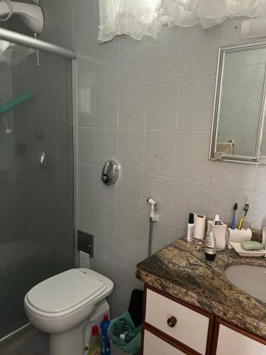 a bathroom with a toilet and a sink and a mirror at Apt Icaraí Niterói Leonardo Davince in Niterói