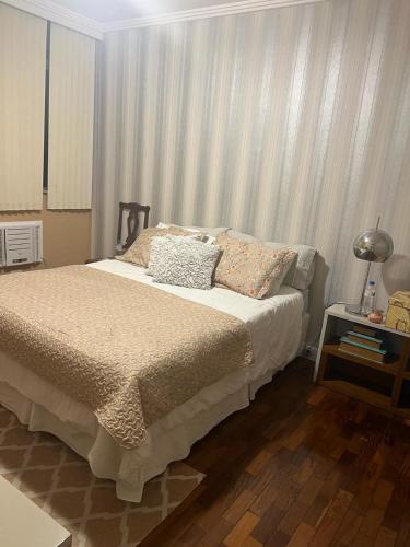 a bedroom with a bed and a table with a lamp at Apt Icaraí Niterói Leonardo Davince in Niterói