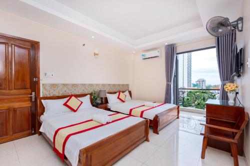 two beds in a room with a window at Biển Vàng Vũng Tàu Hotel in Vung Tau
