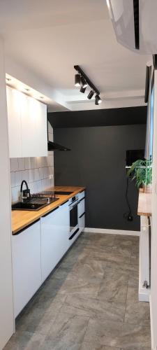 a kitchen with white cabinets and a black wall at Rumia Cichy Zaułek 4 in Rumia