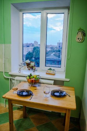 a table with glasses and a bowl of fruit and a window at Babylon Apartments in Rivne