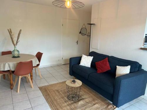 a living room with a blue couch and a table at Le petit coin de Joe Détente Proche Centre bassin in Le Teich