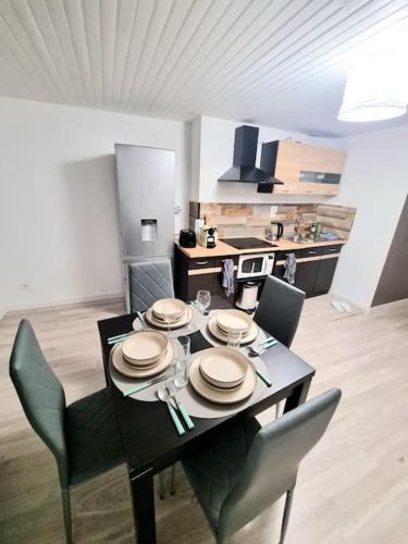 - une table à manger avec des assiettes et des chaises dans la cuisine dans l'établissement Appartement Neuf, à Rive-de-Gier
