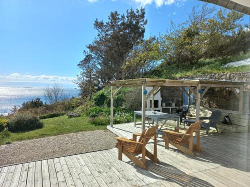 - une terrasse en bois avec une table et des bancs dans l'établissement Maison avec vue exceptionnelle mer, à Ploumoguer