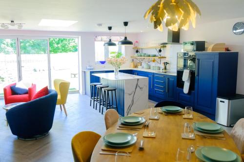 a kitchen with blue cabinets and a table and chairs at The Wave Cottage - 3 Bedroom with off road Parking for 3 Cars or Vans & EV point in Pilning