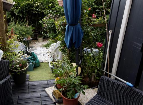 un jardin avec des plantes et un parasol sur une terrasse dans l'établissement Danielle PICARDA, au Mans