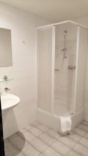 a white bathroom with a shower and a sink at Hotel CB Royal in České Budějovice