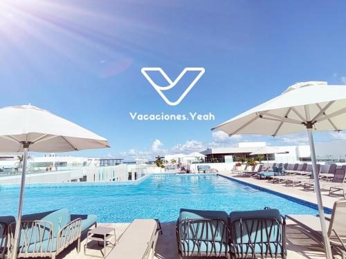 a swimming pool with chairs and umbrellas on a building at IPANA Luxury Apartments by Vacaciones.Yeah in Playa del Carmen