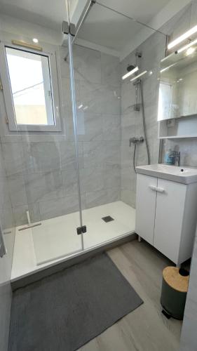 une salle de bain avec une douche avec une porte vitrée dans l'établissement Appartement Marseillan Plage, à Marseillan