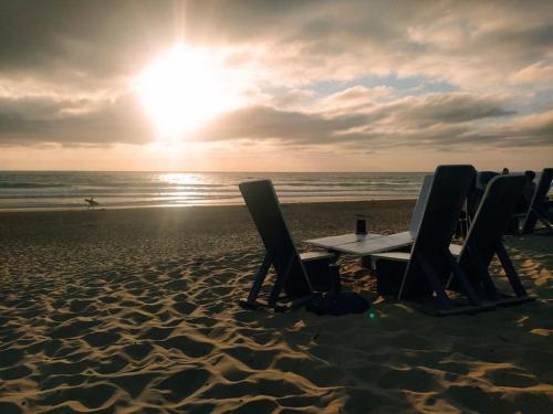 a table and chairs on a beach with the sunset at La belle basco landaise in Mimizan