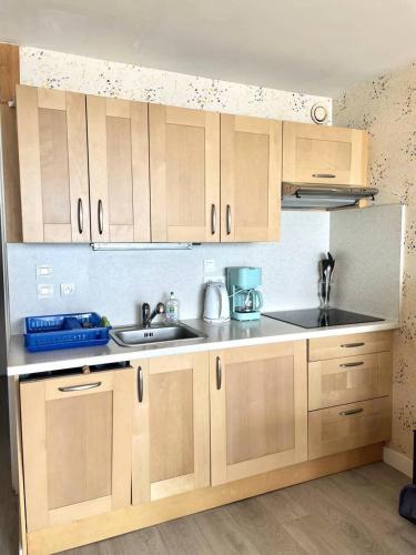 une cuisine avec des armoires en bois et un évier dans l'établissement Résidence De La Mer - Appartement de 28m², en plein cœur du Val André à deux pas de la plage. MAE-6574, à Pléneuf-Val-André