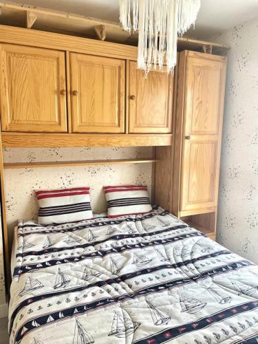 - une chambre avec un lit doté d'armoires en bois et d'un lustre dans l'établissement Résidence De La Mer - Appartement de 28m², en plein cœur du Val André à deux pas de la plage. MAE-6574, à Pléneuf-Val-André