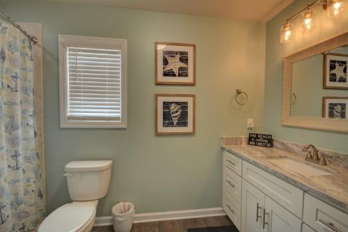 a bathroom with a toilet and a sink and a mirror at Topsail Turvy in North Topsail Beach